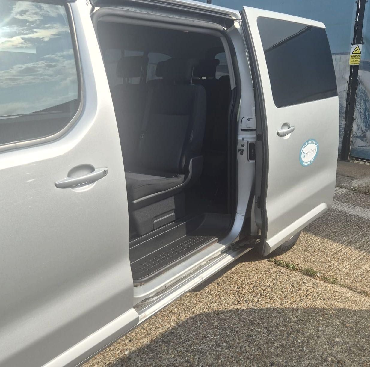 A minibus with its sliding side door and rear door open, showing the seats and the step in.