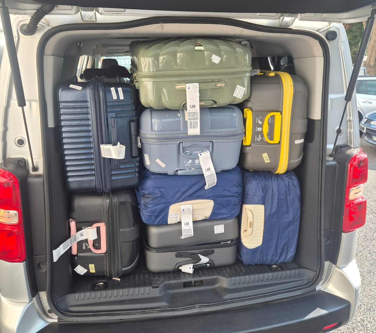 The boot of a minibus packed with a large group's suitcases.