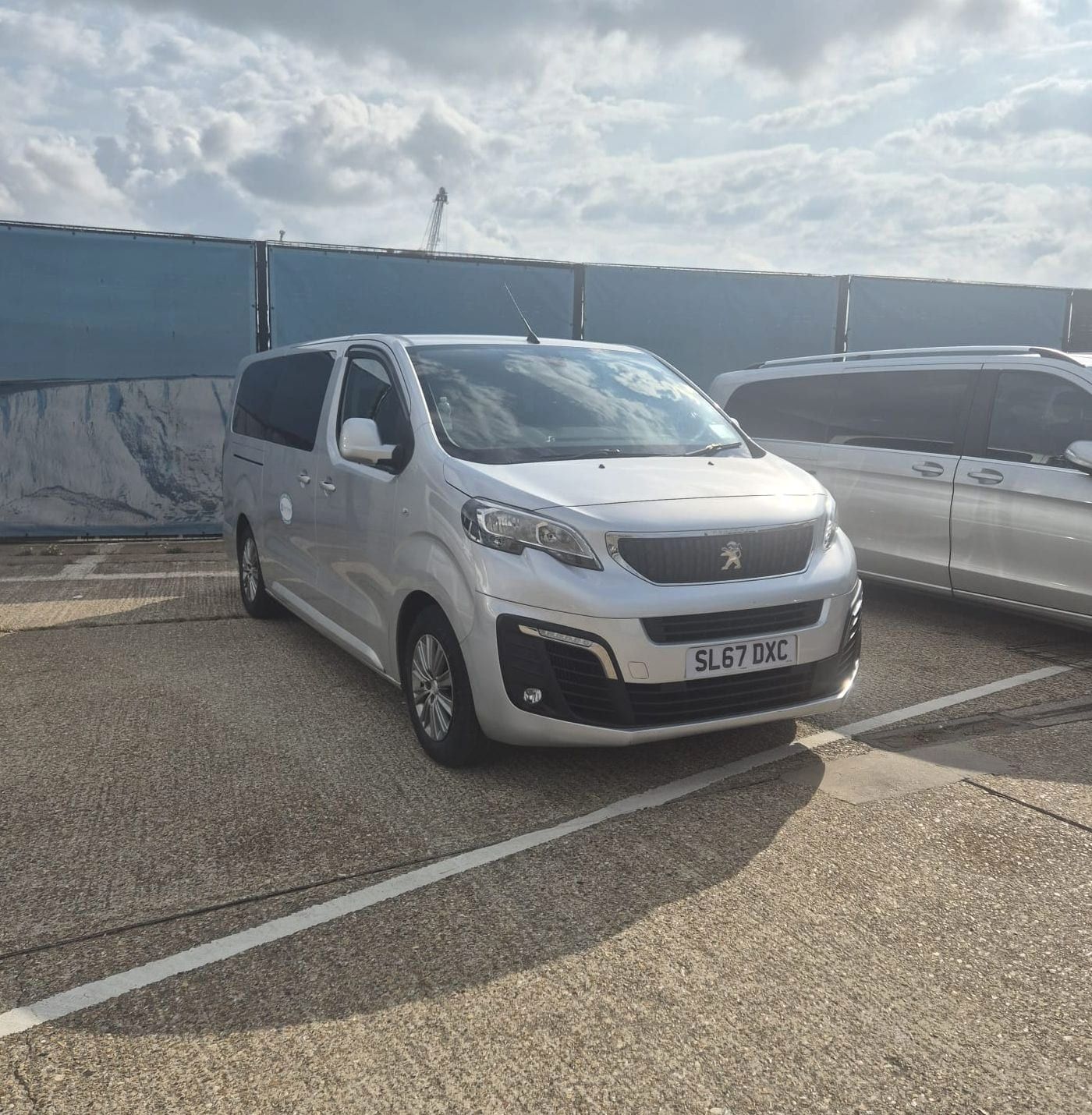 Two silver minibuses parked side by side on tarmac.