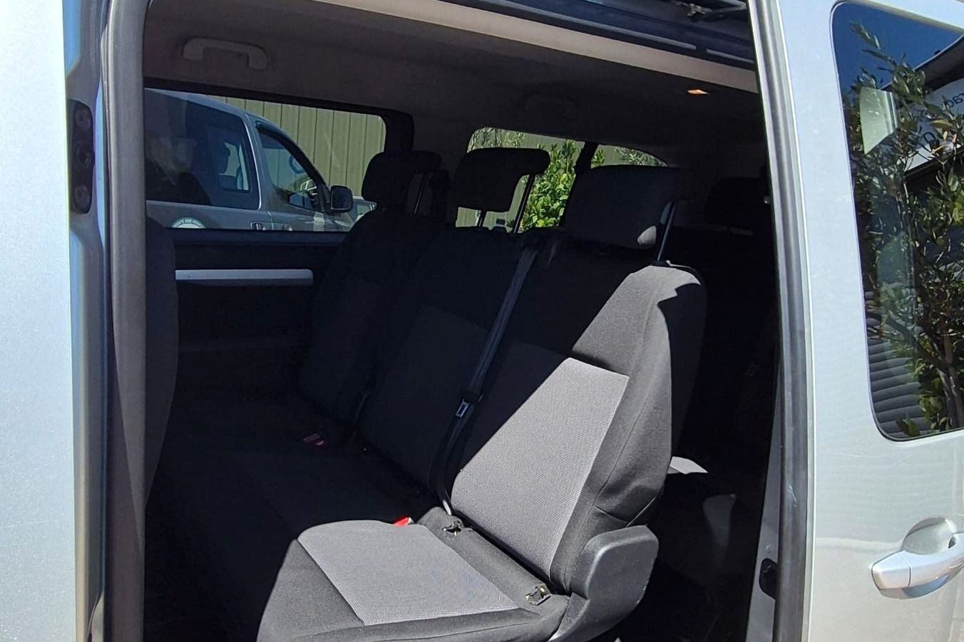 The passenger seats of a minibus, seen through the open side door.